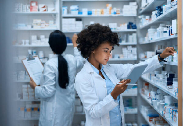 istockphoto-1036131880-612x612 Shot of a young woman doing inventory in a pharmacy on a digital tablet with her colleague in the background